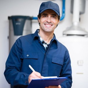 Ein Mann in Arbeitskleidung der ein Klemmbrett haelt